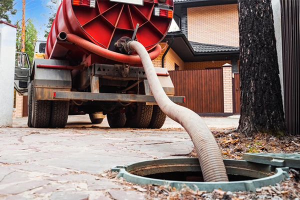 Vacuümwagen leegt een septische put via een zuigslang