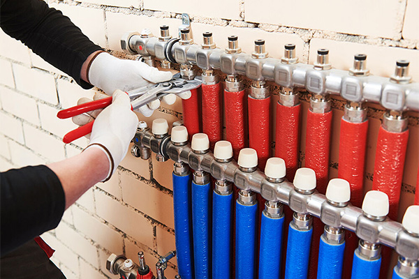 Technicus stelt de verdeler van vloerverwarming af met professioneel gereedschap